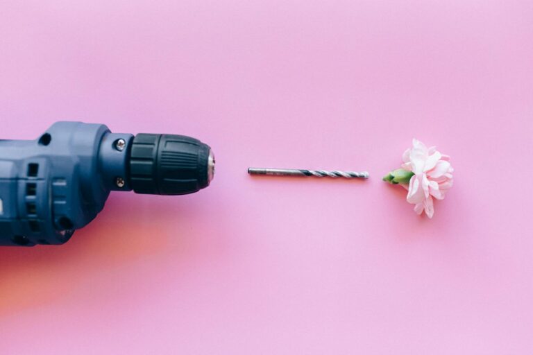 A blue drill and a pink flower creatively arranged on a pink background.